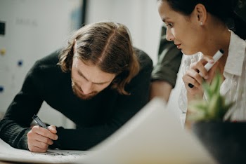 Man Writing on Paper Beside Woman