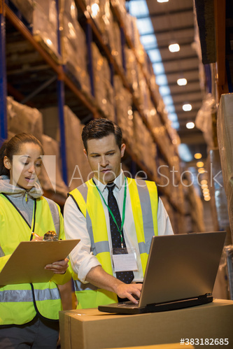 Manager and worker meeting at laptop in distribution warehouse