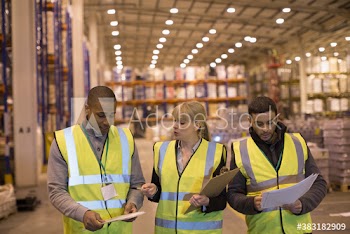 Manager and workers walking and talking in distribution warehouse