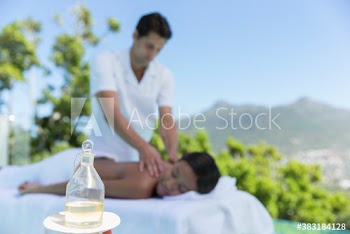 Masseuse giving young woman massage on patio