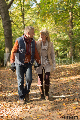 Mature couple holding hands and walking in autumn park
