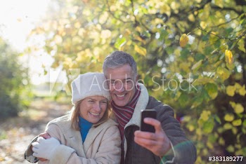 Mature couple taking selfie with smart phone in sunny park