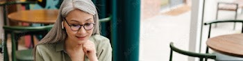 Mature smiling woman in earphone gesturing and using laptop