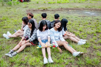 Men and Women Sitting on Grass Forming Circle of Friends
