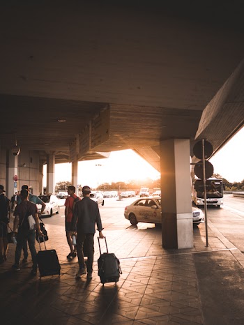 Men Pulling Luggage Bags Along Airport Entrance