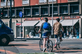 Men Riding Bicycles Traveling on Road Near Red and Gray Building