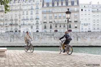 Men riding rented bicycles along Seine River, Paris, France