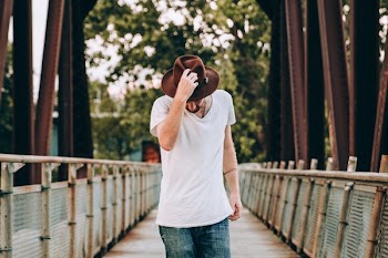 Men's Fashion Walking Across Bridge Holding Hat