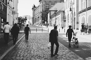 Men Walking on Road With Buildings on the Side
