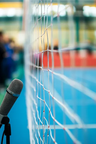 Microphone in foreground with attentive crowd blurred at tennis court