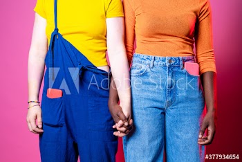 Midsection of young women holding hands standing indoors
