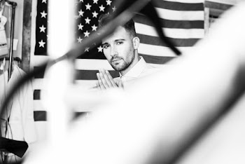 Military Man Standing Beside An American Flag