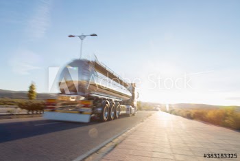 Milk tanker driving on sunny rural road