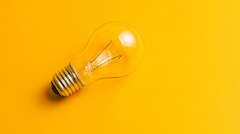 Minimalist Incandescent Light Bulb on Vibrant Yellow Background