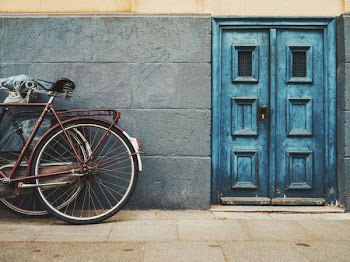 minimalist photography of parked bicycle near blue door