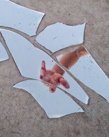 Mirror Fragments on Gray Surface With The Reflection Of A Person"s Arm