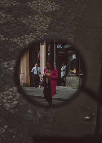 mirror showing woman wearing pink coat walking on street