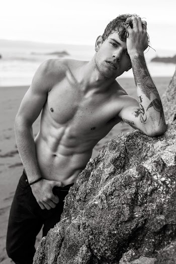 Monochrome Photo of Man Leaning on Rock