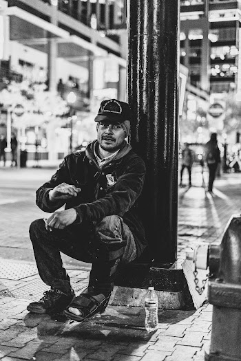 Monochrome Photo of Man Sitting on Lamppost