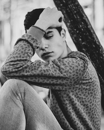 Monochrome Photo of Man Sitting While Touching His Head