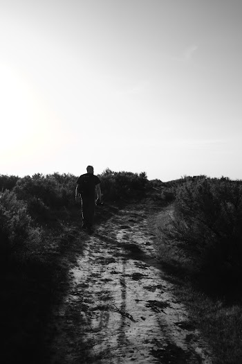 Monochrome Photo of Person Walking On Dirt Road