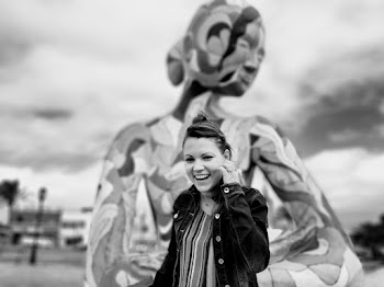 Monochrome Photo of Woman Standing Near a Statue