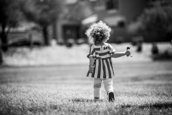 Monochrome Photography of Girl Walking on Grass Field