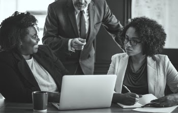 Monochrome Photography of People Near Laptop