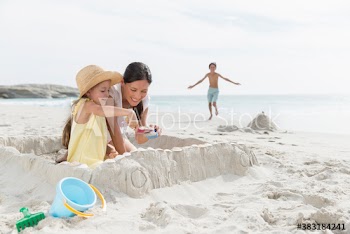 Mother and daughter building sandcastle on beach