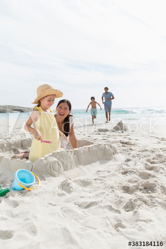 Mother and daughter making sandcastle on beach
