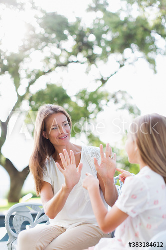 Mother and daughter playing clapping game in sunny park