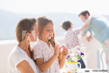 Mother and daughter with flower on sunny balcony