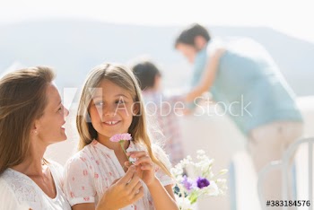 Mother and daughter with flower on sunny balcony