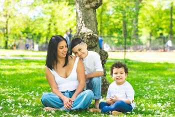 mother and her children Sitting on Green Grass Field