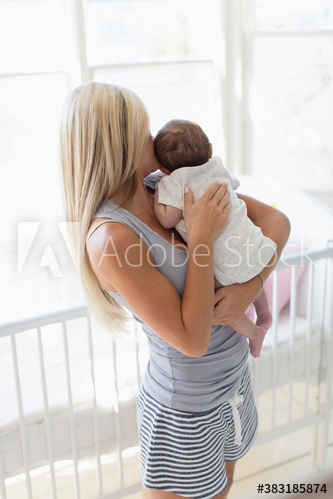 Mother cuddling baby daughter in baby nursery