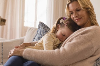 Mother embracing her sleeping daughter in arms