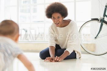 Mother encouraging baby son crawling on floor