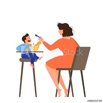 Mother feed her little baby sitting in highchair