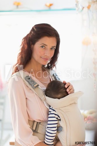 Mother holding baby daughter in baby carrier