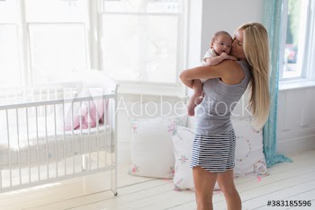 Mother holding baby daughter in baby nursery