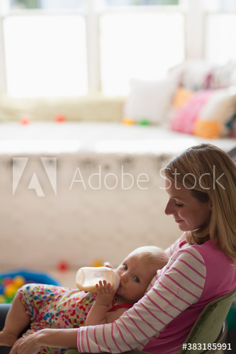 Mother holding baby daughter with baby bottle