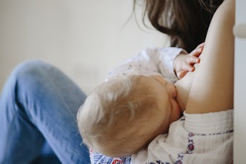 Mother is breastfeeding a little blond baby Free Photo