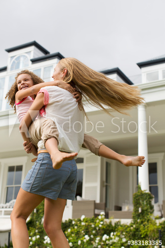Mother spinning daughter in backyard