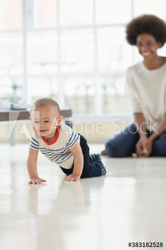 Mother watching cute baby boy crawling on floor