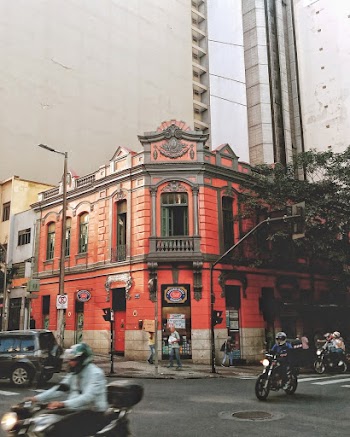 Motorcycles Passing by Red Building