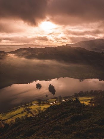 mountain and body of water under brown skies
