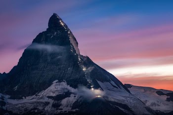 mountain covered with snow under orange and blue sky at daytime