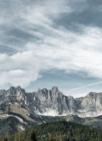 mountain near forest under clouds