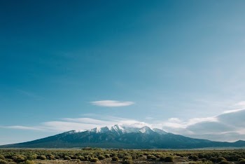 mountain near grass field under cloudy sky