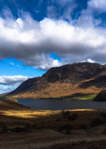 Mountains Beside a Lake Under White Clouds